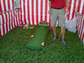 A man playing the Down the Clown Carnival Game in a tent.