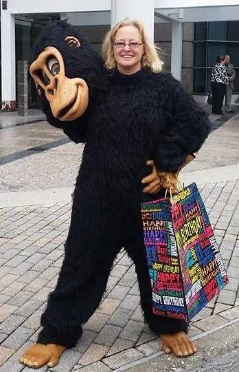 A woman dressed as a gorilla holding shopping bags, delivering a Singing Telegram.