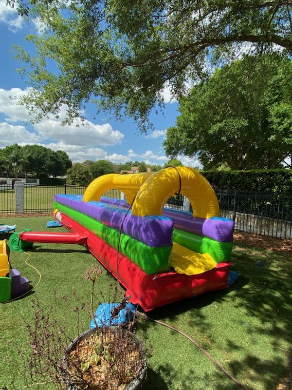 A colorful inflatable Single Lane Slip and Slide in a grassy area.