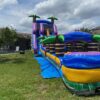 The Cowabunga Slide is a large inflatable water slide situated in a lush grassy area.