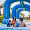 A man and a child playing in an inflatable water slide.