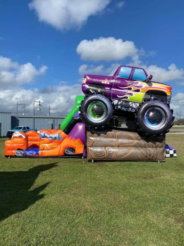 A Monster Truck Bounce House and Slide Combo in a grassy field.