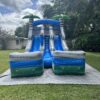 The Surfs Up Slide is a vibrant blue and green water slide located in a backyard.